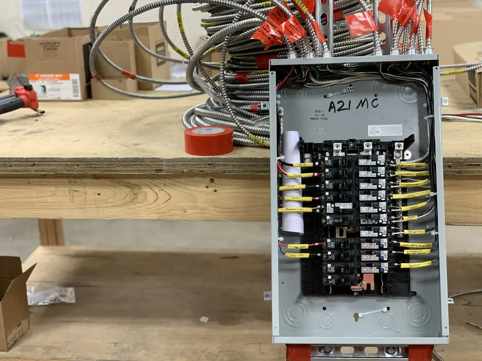 Illustrative photo: a breaker panel on a workbench, wired and labeled.